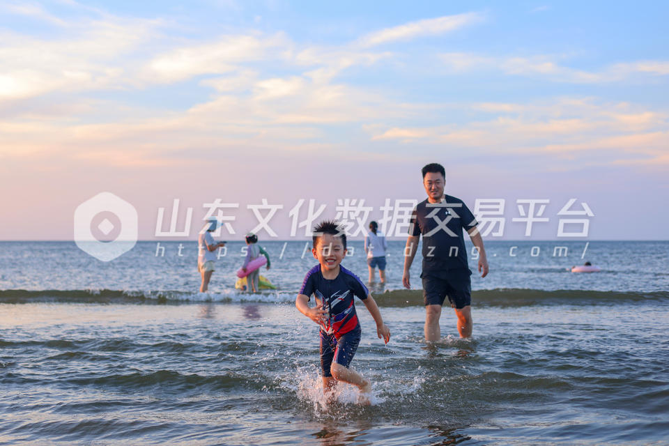 小朋友在夕阳下踏浪欢笑。