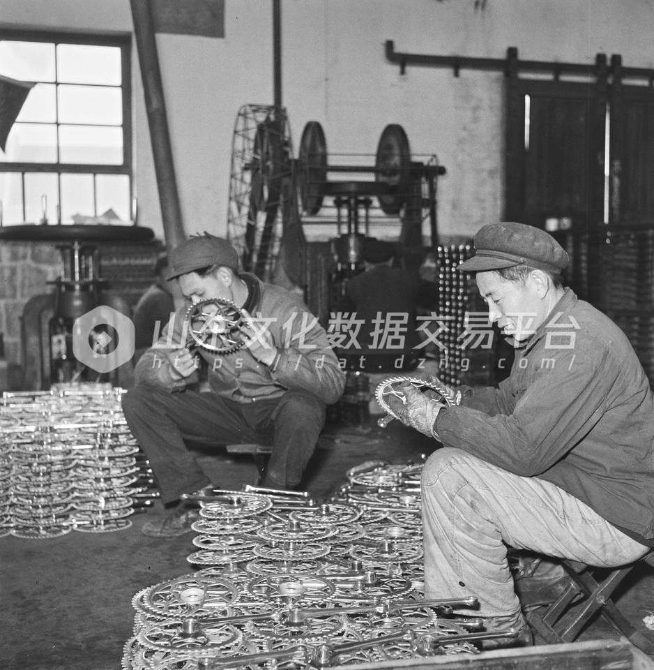 青岛自行车厂装配车间工人装配车轮。